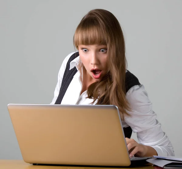 Jovencita conmocionada está mirando a un ordenador portátil — Foto de Stock