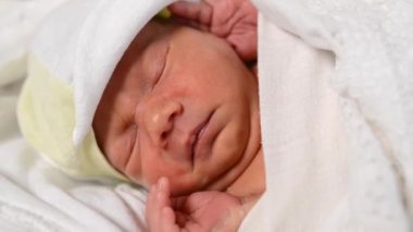 Beyaz dantelli çarşaflarda kestirip duran yeni doğmuş şirin bebeğe yakın çekim. Beyaz bir bezin içinde dinlenen tatlı bir çocuk. Uyuyan bebek kavramı.