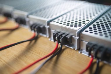 Metal ağ güç kaynağı ve kablolarının kapatıldığı kutular yüksek teknolojili bilgisayar üretiminde ahşap bir masanın üzerinde. Yüksek Teknoloji ve Bilgisayarı Kabul Et