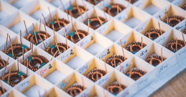 Birçok bükülmüş bakır bobin, daha fazla elektronik ekipman üretimi için kompartımanlarda yatıyor. Tıbbi ekipman üretimi için fabrika konsepti