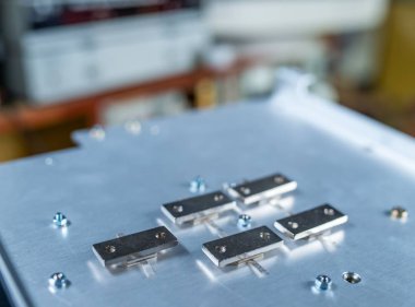 Büyük bir demir platforma vidalanmış beş metal plaka yakın çekim. Endüstriyel ekipman ve tıbbi veya askeri teçhizat üretimi için ayrıntı kavramı