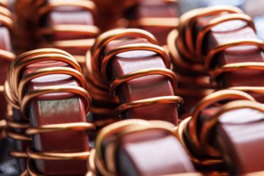 Sanayi ve yerli ekipman, buzdolabı ve dondurucu üretimi için fabrikadaki demir tozu çekirdeğine sarılı sarı ve mavi bobinlerin yakın çekimleri. Verici üretimi kavramı