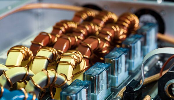 Top view close-up of blue yellow and red coils wrapped in copper wire connected to a microcircuit. Concept of household manufacturing parts and shipbuilding production