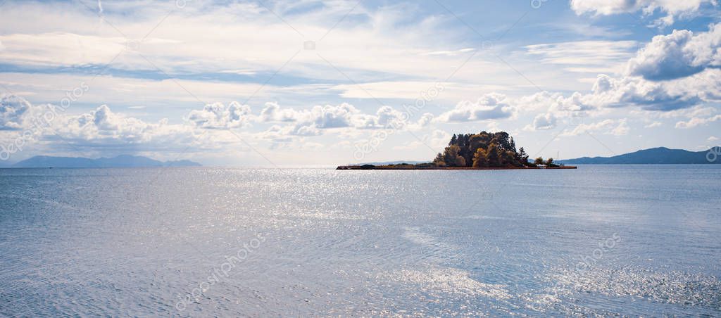 Kerkyra green bay with crystal clear water, big stones on Corfu island, Greece. Beautiful landscape of Ionian sea beach. Sunny weather, blue sky.