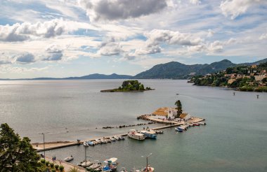 Korfu Adası, Yunanistan 'daki inanılmaz körfez. Renkli şezlongları, yeşil dağlardaki ağaçları ve turistler için otelleri olan İyon deniz plajının güzel manzarası..