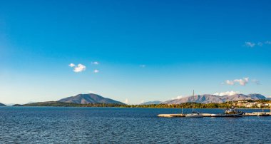 Korfu Adası, Yunanistan 'daki inanılmaz körfez. Renkli şezlongları, yeşil dağlardaki ağaçları ve turistler için otelleri olan İyon deniz plajının güzel manzarası..