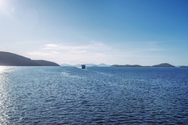 Yunanistan 'ın Korfu adası yakınlarında bir yolcu gemisiyle inanılmaz bir deniz feneri. İyon denizinin güzel manzarası, arka planda dağlar. Güneşli hava.