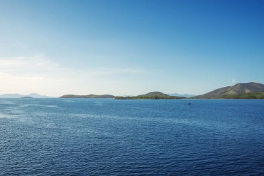 Korfu Adası, Yunanistan 'daki inanılmaz körfez. Renkli şezlongları, yeşil dağlardaki ağaçları ve turistler için otelleri olan İyon deniz plajının güzel manzarası..