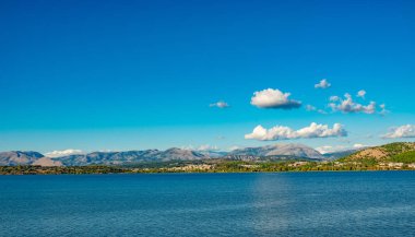 Korfu Adası, Yunanistan 'daki inanılmaz körfez. Renkli şezlongları, yeşil dağlardaki ağaçları ve turistler için otelleri olan İyon deniz plajının güzel manzarası..