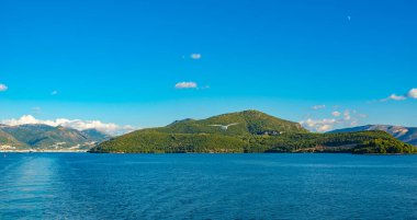 Korfu Adası, Yunanistan 'daki inanılmaz körfez. Renkli şezlongları, yeşil dağlardaki ağaçları ve turistler için otelleri olan İyon deniz plajının güzel manzarası..