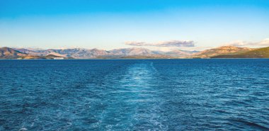 Korfu Adası, Yunanistan 'daki inanılmaz körfez. Renkli şezlongları, yeşil dağlardaki ağaçları ve turistler için otelleri olan İyon deniz plajının güzel manzarası..