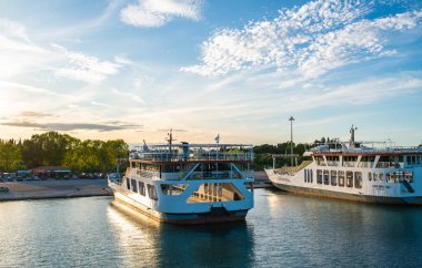 Kerkyra, Korfu Adası, Yunanistan - 4 Ekim 2019: İyon Denizi yakınlarındaki iki feribotun görüntüsü. Yeşil ağaçlı, güneşli, Korfu adasının güzel manzarası. Turistleri bekleyen tekneler.