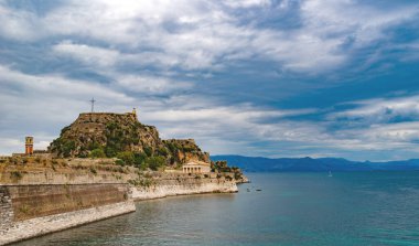 Korfu Adası, Yunanistan 'daki inanılmaz körfez. Renkli şezlongları, yeşil dağlardaki ağaçları ve turistler için otelleri olan İyon deniz plajının güzel manzarası..