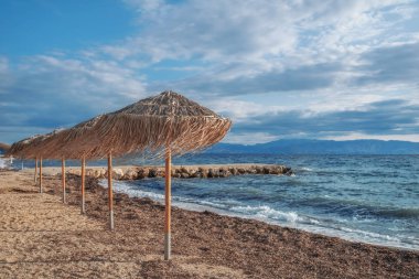 Yunanistan 'ın Korfu adasında kristal berrak suyla inanılmaz bir körfez. Saman şemsiyeli, güneşli bir İyon sahili manzarası..