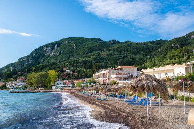 Kerkyra, Korfu Adası, Yunanistan - 4 Ekim 2019: Yunanistan 'ın Korfu adasındaki Paleokastritsa adasında kristal berrak suyla inanılmaz körfez. Saman şemsiyeli güzel İyon sahili manzarası.