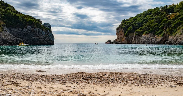 Korfu Adası, Yunanistan 'daki inanılmaz körfez. Renkli şezlongları, yeşil dağlardaki ağaçları ve turistler için otelleri olan İyon deniz plajının güzel manzarası..