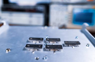 Büyük bir demir platforma vidalanmış beş metal plaka yakın çekim. Endüstriyel ekipman ve tıbbi veya askeri teçhizat üretimi için ayrıntı kavramı