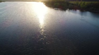 Bir gölün üzerinde uçmak ve suyu aydınlatan güneş..