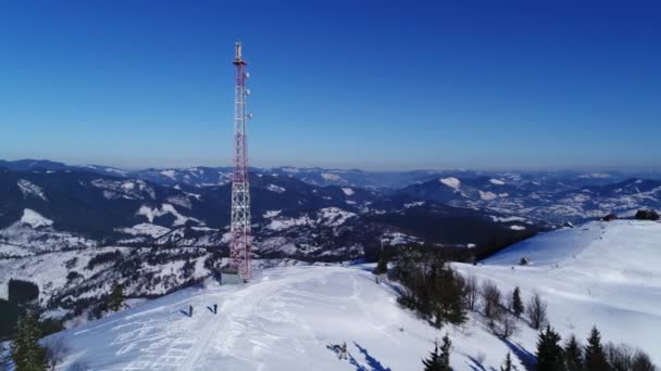 無線通信塔の上を飛んで 山の雪は冬の風景をカバー — ストック動画