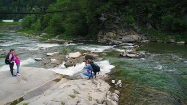 カルパティア山脈の緑の森の川の美しい水の流れの近くの人々 — ストック動画