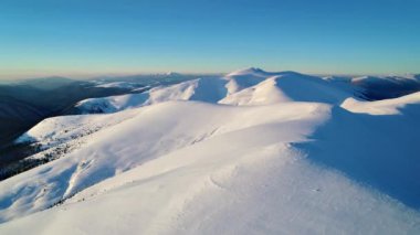 Akşam güneşiyle aydınlatılan Karlı Dağların Üzerinden Uçuş
