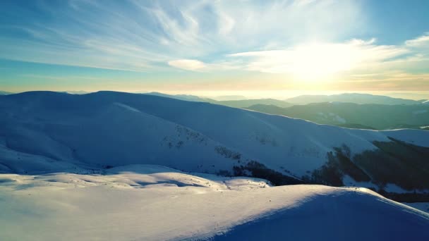 夕日に照らされた雪の山の上を飛ぶ — ストック動画