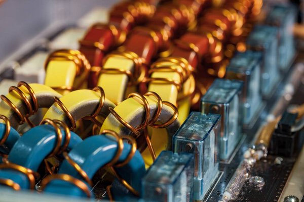 Top view close-up of blue yellow and red coils wrapped in copper wire connected to a microcircuit. Concept of household manufacturing parts and shipbuilding production