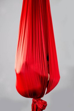 Kimliği belirsiz küçük bir kız gri bir arka planda asılı kırmızı bir eşarba saklanmış. Hava akrobasisi ve jimnastik kavramı. Reklam alanı