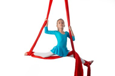 Küçük akrobat kız beyaz arka planda kırmızı bir hava şeridine tutunarak havada uçuyor. Akrobasi konsepti. Reklam alanı