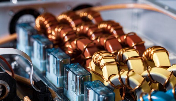 Top view close-up of blue yellow and red coils wrapped in copper wire connected to a microcircuit. Concept of household manufacturing parts and shipbuilding production