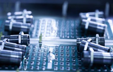 Yakından metal fındıklar ve silindirler pompa ve kazan fabrikasındaki yeşil bir mikro devrede yatıyor. Bahçe ve ev aletleri kavramı