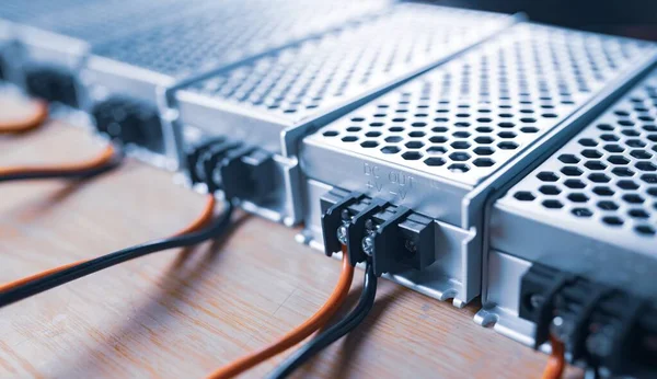 Close up of the metal mesh cases of power supply and wires are on a wooden table at the production of high-tech computers. Concept High Tech and Computer