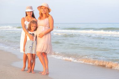 Anne ve kızları akşamları sahilde. Doğal Ebeveynlik Konsepti.