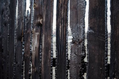 Özel bir evde çıkan yangından sonra yanmış çit tahtaları. Dikkatsiz ve düşüncesizce ateş etmenin sonuçları..