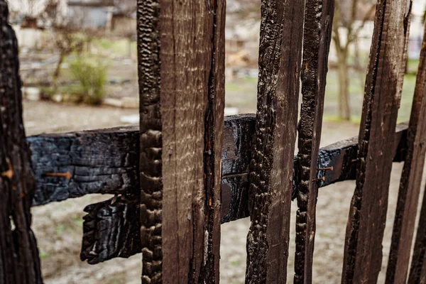 Burnt fence boards after a fire in a private house. The consequences of not careful and thoughtless handling of fire.