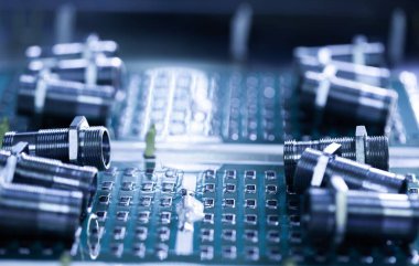 Yakından metal fındıklar ve silindirler pompa ve kazan fabrikasındaki yeşil bir mikro devrede yatıyor. Bahçe ve ev aletleri kavramı