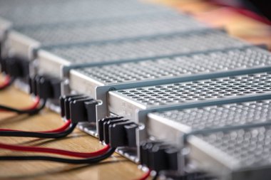 Metal ağlar, yüksek teknolojili bilgisayar üretiminde ahşap bir masanın üzerinde güç kaynağı ve kablolar bulunuyor. Yüksek teknoloji ve endüstriyel üretim kavramı