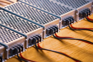 Metal ağlar, yüksek teknolojili bilgisayar üretiminde ahşap bir masanın üzerinde güç kaynağı ve kablolar bulunuyor. Yüksek teknoloji ve endüstriyel üretim kavramı