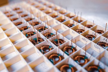 Birçok bükülmüş bakır bobin, daha fazla elektronik ekipman üretimi için kompartımanlarda yatıyor. Tıbbi ekipman üretimi için fabrika konsepti