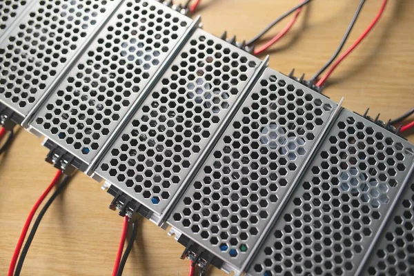 Top view of the metal mesh power supply of the microcircuit are on a wooden table at the production of high-tech computers. Concept of high technology and office equipment