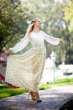 Park 'ta dans eden çekici bir kadının ön görüntüsü. Zarif bir elbise giymiş, saçları çiçek gibi olan çekici bir kız. Güzellik ve zarafet kavramı.