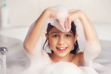 Kız banyoda banyo yapar ve köpükle oynar. Büyük bir düşüş. Baloncuk üfleme