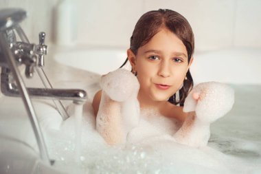 Kız banyoda banyo yapar ve köpükle oynar. Büyük bir düşüş. Baloncuk üfleme