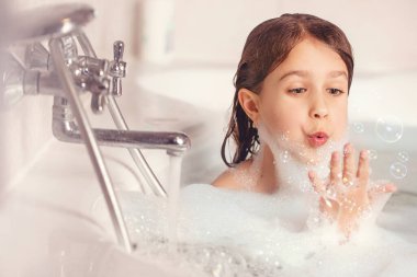 Kız banyoda banyo yapar ve köpükle oynar. Büyük bir düşüş. Baloncuk üfleme