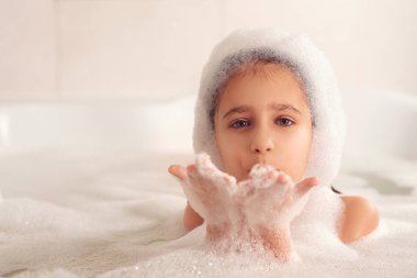 Kız banyoda banyo yapar ve köpükle oynar. Büyük bir düşüş. Baloncuk üfleme