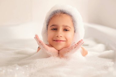 Kız banyoda banyo yapar ve köpükle oynar. Büyük bir düşüş. Baloncuk üfleme
