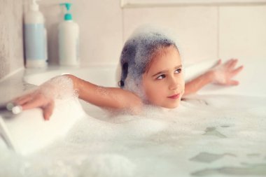 Kız banyoda banyo yapar ve köpükle oynar. Büyük bir düşüş. Baloncuk üfleme