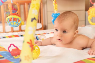 Küçük çocuk, çocuk gelişimi için tasarlanmış çok renkli bir halıda sürünüyor. Aktif sağlıklı çocuk kavramı..