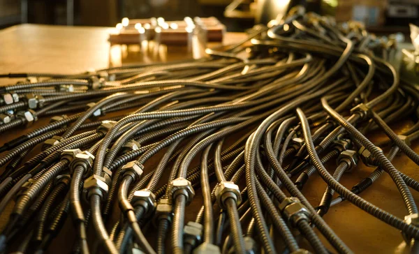 Close-up of a huge bunch of metal flexible tubes with nuts interconnected in a factory. The concept of modern electronic and IT technology.