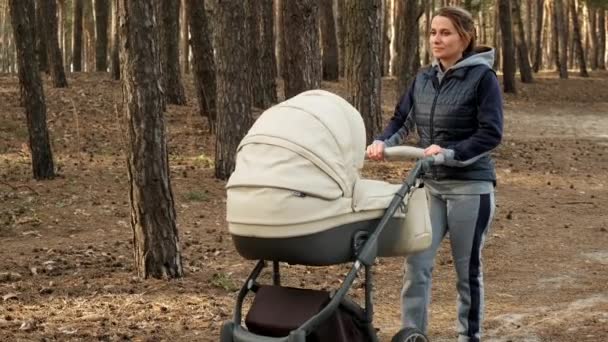 一个带着婴儿车的女人走在春天的森林里 呼吸着新鲜空气 不怕病毒 妈妈和一个小孩在森林里散步 Uhd摄像机 2X慢动作 — 图库视频影像